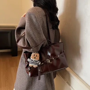 Détail du sac cabas en cuir marron brillant avec boucle réglable et breloque ours