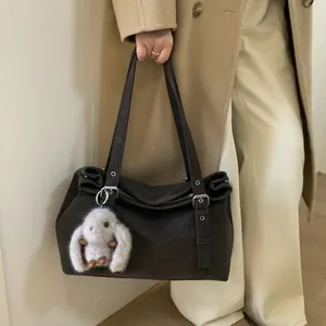 Détail du sac bandoulière marron foncé mat avec anneaux argentés et charm lapin blanc pelucheux