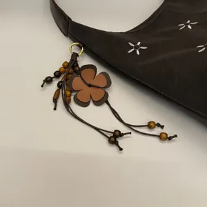 Détail du sac cabas vintage en cuir marron avec broderie florale et breloque à pompon