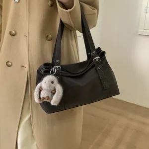 Détail du sac bowling marron foncé en daim avec boucle décorative et breloque en peluche
