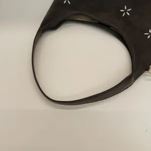 Détail du sac cabas en daim marron foncé avec broderie de fleurs blanches et bandoulière cuir