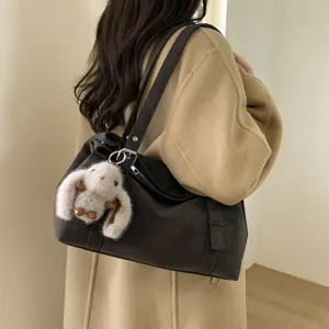Détail d'un sac cabas minimaliste sombre avec texture mate et charme lapin en peluche