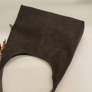 Détail du sac hobo rétro marron café avec pendentif en perles de bois et surpiqûres