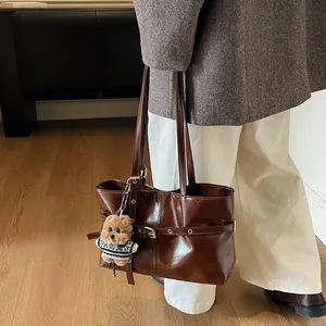Détail du sac cabas en similicuir marron foncé avec charme d'ours en peluche et boucle métal
