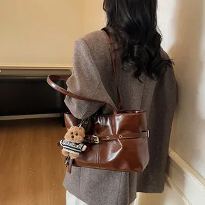 Détail d'un sac cabas marron foncé en similicuir avec boucle et pendentif ours en peluche