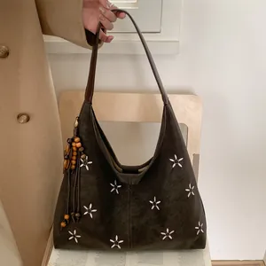 Détail du sac cabas marron foncé avec broderie florale blanche et pompons en perles de bois