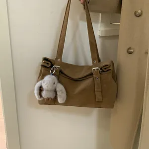 Détail du sac bowling marron avec boucles argentées et breloque lapin en peluche