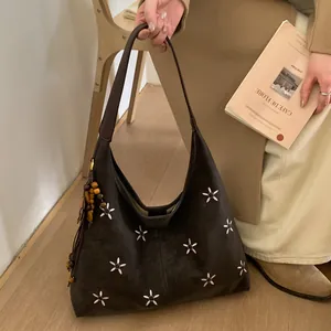 Détail du sac hobo marron foncé avec broderie florale et pompon décoratif en perles de bois