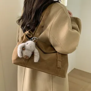 Détail du sac bandoulière marron rétro avec pendentif lapin en peluche et boucle métal