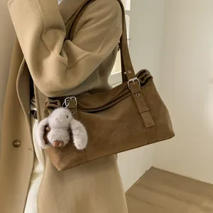 Vue détaillée d'un grand sac à bandoulière marron muni d'un charmant lapin blanc en peluche