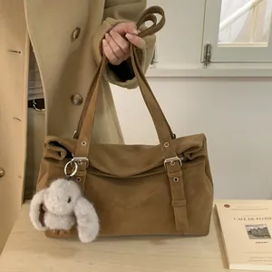 Détail d'un sac à main en daim marron avec sangles à boucles et breloque lapin en peluche