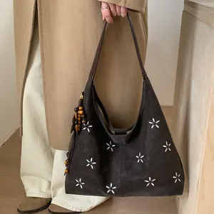 Gros plan du sac cabas vintage marron foncé avec broderies florales et pendentif glands