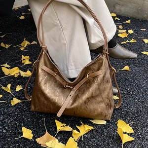 Close-up of vintage brown tote bag with metallic sheen on autumn ginkgo leaves background