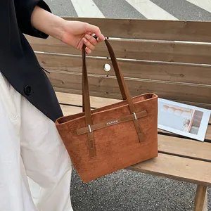 Λεπτομέρεια καφέ σουέτ τσάντας tote με ασημένια αγκράφα και λογότυπο μάρκας
