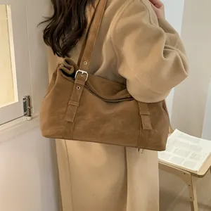 Gros plan d'un sac hobo en daim marron avec détails argentés et bandoulière réglable