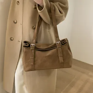 Détail d'un sac à bandoulière en daim marron avec boucle argentée réglable sur un modèle