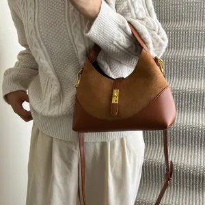 Detail shot of the golden piston clasp and suede leather texture of the hobo bag