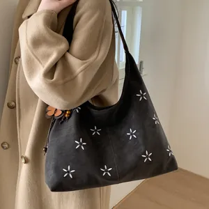 Détail du sac hobo vintage avec broderies florales et pendentif en perles chic