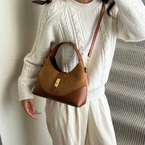Detail of contrast suede and leather hobo bag with a gold twist lock on white sweater