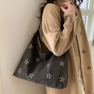 Détail du sac cabas gris foncé avec broderie florale porté par un mannequin en manteau