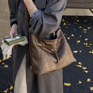 Close-up of vintage brown tote bag with metal buckle on autumn ginkgo leaves background