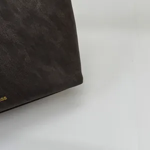 Detailansicht der dunkelbraunen Lederstruktur mit goldener GS-Prägung auf der Tasche