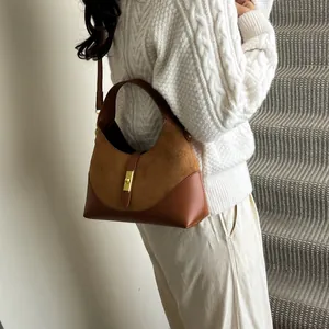 Detail of hobo bag featuring brown suede and leather stitching with gold metal clasp lock