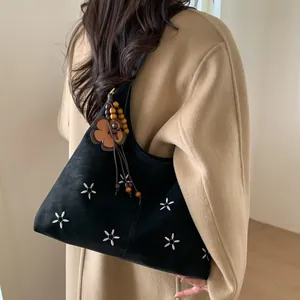 Détail du cabas en daim noir avec broderie de fleurs blanches et breloque en perles de bois