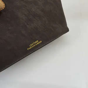Nahaufnahme der dunkelbraunen Lederstruktur mit goldener Fashion & Bags Aufschrift