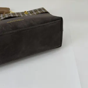 Nahaufnahme von Vintage-Karomuster und Golddruck auf einer dunkelbraunen Ledertasche