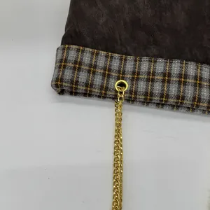 Detail von Vintage-Karostoff mit goldener Metallkette auf brauner Leder-Tragetasche