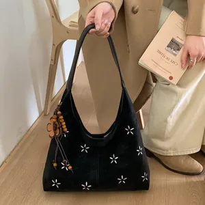 Broderie détaillée de fleurs blanches sur sac fourre-tout en daim noir avec pompon bohème