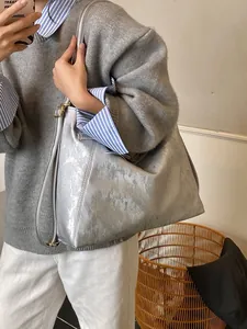 Silver metallic vintage tote bag with pleated texture and leather straps worn by model