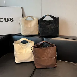 Dettaglio di quattro borse a secchiello in pelle PU testurizzata nei colori beige, nero e bianco