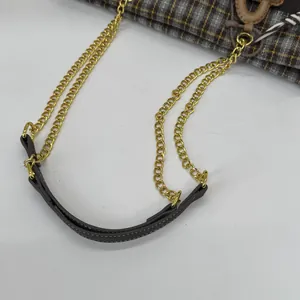 Detail der Vintage-Karotasche mit goldenen Kettenriemen und dunkelbraunen Lederpolstern