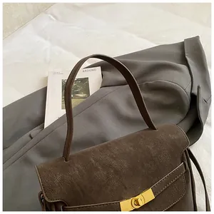 Detalle del bolso vintage marrón oscuro en cuero mate con hebilla de metal dorado elegante
