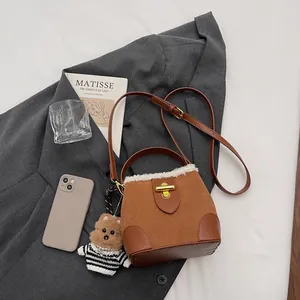 Détail du sac seau en daim marron avec bordure en peau lainée et fermoir doré
