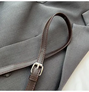 Dettaglio tracolla in pelle marrone scuro con fibbia argento e cuciture della borsa