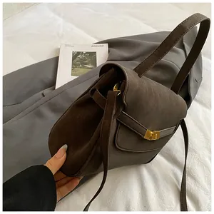 Detalle de bolso tote mate marrón oscuro con cierre de giro dorado y estilo retro suave