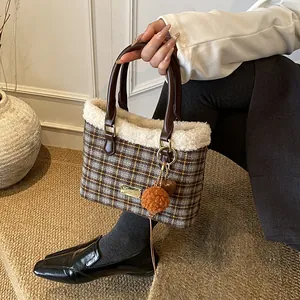 Detalle del bolso tipo cubo a cuadros con borde de felpa blanca y colgante de piel