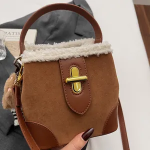 Gros plan du sac seau en daim marron avec garniture en fausse fourrure blanche et fermoir doré