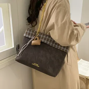 Vintage-Einkaufstasche in Braun mit Karomuster und goldener Kette an einem Modell