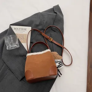 Détail du sac seau en daim avec bordure en peau lainée et bandoulière réglable