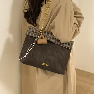 Details der braunen Vintage-Tasche mit goldener Kette und modischem Karostoff-Besatz