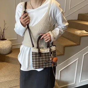 Detalle de bolso cubo de cuadros marrones con ribete de piel sintética y colgante de corazón