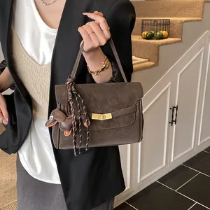 Detalle de bolso tote de cuero marrón café con cierre dorado y colgante de perro