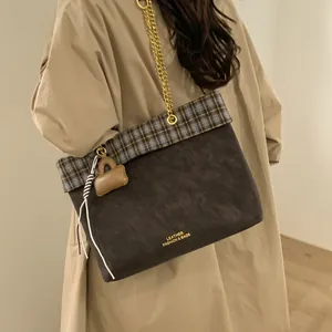 Nahaufnahme der braunen Vintage-Tasche mit Karomuster-Besatz und Mini-Taschenanhänger