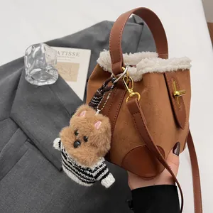 Détail du sac seau en daim avec bordure en fausse fourrure blanche et charm de chien