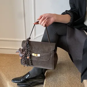 Detalle de bolso tote de cuero marrón vintage con cierre dorado y colgante de perro