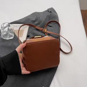 Détail du sac bandoulière en daim marron vintage avec bordure peluche et boucle dorée